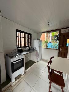 a kitchen with a stove and a refrigerator and a table at Charming Chalet Village Historic Center in Ilhabela