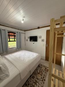 a bedroom with a bed and a television in it at Charming Chalet Village Historic Center in Ilhabela