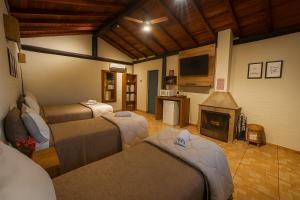a living room with three beds and a fireplace at Pousada A Mata que Canta in Socorro