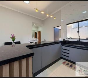 a kitchen with white cabinets and black counter tops at Cantinho do Descanso in Peruíbe