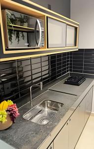 eine Küche mit Spüle und Mikrowelle in der Unterkunft Studios super modernos, completos e equipados no centro de Pará de Minas in Pará de Minas