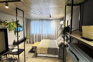 ein Schlafzimmer mit einem Bett und einem großen Fenster in der Unterkunft Studios super modernos, completos e equipados no centro de Pará de Minas in Pará de Minas