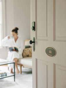 a woman sitting on a couch reading a book at Guestroom in Old Town | Steps to Lake & Everything in Niagara on the Lake