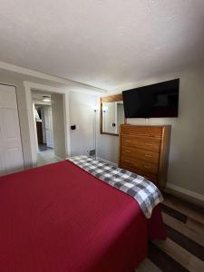 a bedroom with a red bed and a flat screen tv at Mountain Villas Condo Retreat for 12 in Boyne Falls +38 photos