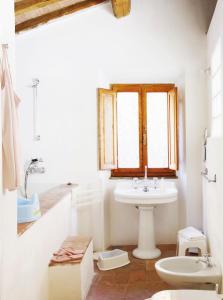 a white bathroom with a sink and a window at Casa Delle Aque in Montecatini Val di Cecina