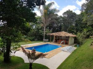 a swimming pool in a yard with a house at Sítio com piscina e vista em Macacos - Nova Lima in Nova Lima