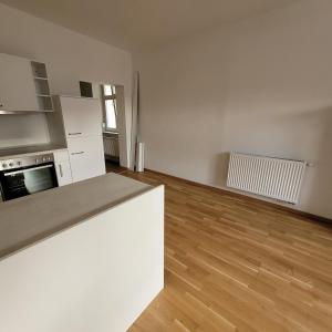 ein leeres Wohnzimmer mit einer Küche und Holzböden in der Unterkunft Bahnhofstraße III Apartment in Straubing