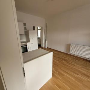 Ein leerer Raum mit einer weißen Küche und Holzböden in der Unterkunft Bahnhofstraße III Apartment in Straubing + 2 Fotos