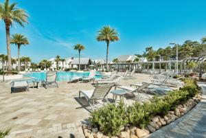 a pool at a resort with chairs and palm trees at Prominence 30A - Holiday House in Watersound Beach