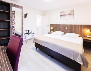 a bedroom with a large bed and a chair at Pension Altes Backhaus in Herzogenaurach