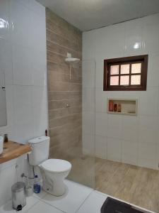 a white bathroom with a toilet and a shower at Chácara Condomínio Cristal Azul Mairinque in Mairinque
