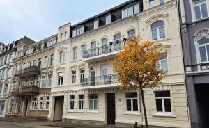 a large white building with a tree in front of it at Amadeus Loft in Wilhelmshaven