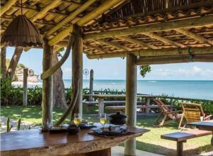 Uma mesa de madeira com taças de vinho e vista para o oceano. em Casa Mar em Porto Seguro