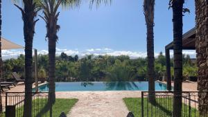 Blick auf einen Swimmingpool zwischen zwei Palmen in der Unterkunft Villa Dar Waw Marrakech in Tameslouht
