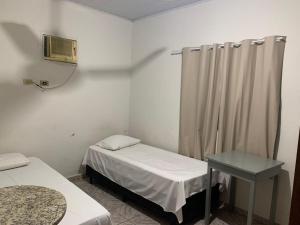 アキダウアナにあるHotel Aquidauanenseのベッド2台とテーブルがある小さな部屋