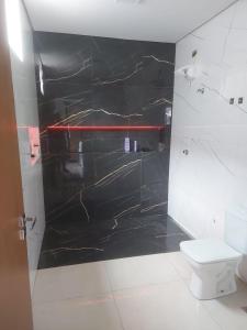 La salle de bains est pourvue d'un mur en marbre noir et de toilettes. dans l'établissement Casa de alto padrao na beira do lago Corumba IV, à Brasilia