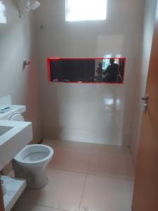 une salle de bain blanche avec toilettes et fenêtre dans l'établissement Casa de alto padrao na beira do lago Corumba IV, à Brasilia