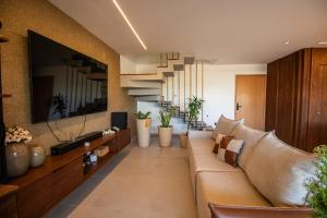 un soggiorno con un divano e una TV di Triplex 3 Suítes Piscina e Hidro para até 12 pessoas a Tatuamunha