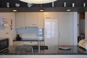a kitchen with white cabinets and a black counter top at Stockenmatt Haus 2, Wohnung 22 in Stalden +6 photos
