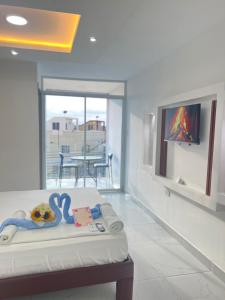 Habitación con cama, TV y balcón. en Hostal Las Orquideas 2, en Manta