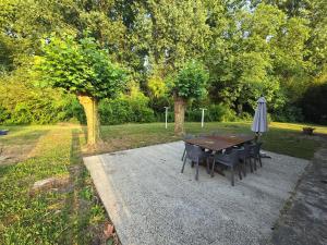 a table and chairs and an umbrella in a park at Gîte Horizons Landais Séjour professionnel et vacances dans les Landes in Pontonx-sur-lʼAdour