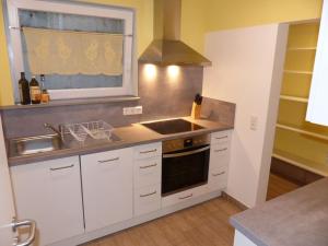 eine Küche mit weißen Schränken und einer Spüle und einem Herd in der Unterkunft Ferienwohnung Paula in Sankt Johann + 8 Fotos