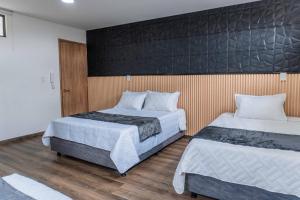 a bedroom with two beds and a black wall at Hotel Salinero - Zipaquirá in Zipaquirá