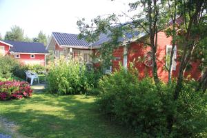 a red house with a garden in front of it at Puolukkamaan Pirtit Cottages in Lampsijärvi