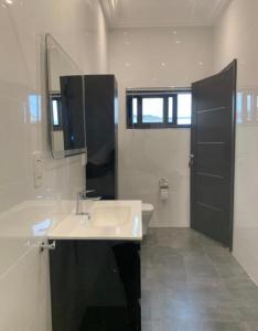a white bathroom with a sink and a mirror at Legacy Square Apartment in Accra