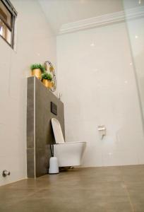 a bathroom with a toilet in a white room at Legacy Square Apartment in Accra