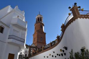 a building with a clock tower in the background at Zentral Gelegene Wohnung in Cómpeta +17 photos