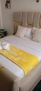 a bed with a yellow blanket on top of it at Urban Nest suites in Kisii