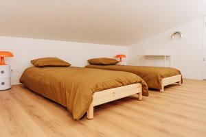 two beds in a white room with wood floors at Appartement centre village Tavel in Tavel