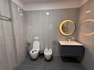 een badkamer met een toilet, een wastafel en een spiegel bij Modern 2BR Near City Ring & Main Road Access in Tirana +11 foto's