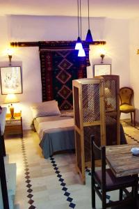 a bedroom with a bed and a table and chairs at L'artisan in Harqalah
