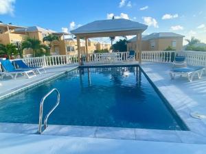 a swimming pool with chairs and a gazebo at Modern Studio in Pelican with pool-walk to Beach, Dining, Entertainment in Simpson Bay