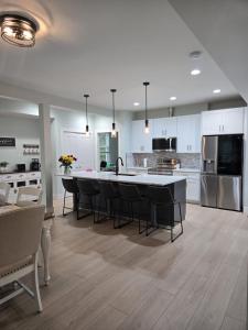 a kitchen with white cabinets and a large island with black chairs at The Backwoods Paradise in Logan