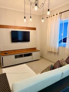 un salon avec une télévision et un canapé dans l'établissement Grazi Arraial Beach - Centro Arraial do Cabo, à Arraial do Cabo