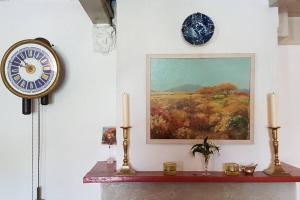 a clock on a wall with two candles on a shelf at Charming house in Westenschouwen in Burgh Haamstede