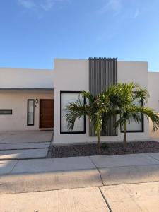 a house with two palm trees in front of it at Modern beach house in San Carlos in San Carlos