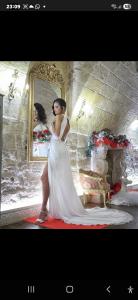 Eine Frau in einem weißen Kleid, die vor einem Spiegel steht. in der Unterkunft L' alcova di Federico in Trani