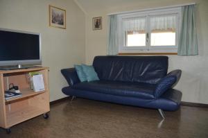 a living room with a blue leather couch and a television at Ferienwohnung Sutter In Brülisau Bei Appenzell in Rüthi