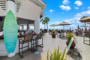 eine Terrasse mit Tischen und Stühlen sowie einem Surfbrett in der Unterkunft GP58: 58 Grand Pavilion in Isle of Palms