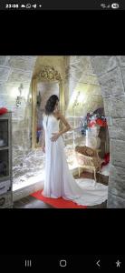 Eine Frau in einem weißen Kleid, die vor einem Spiegel steht. in der Unterkunft L' alcova di Federico in Trani