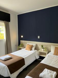 ein Schlafzimmer mit zwei Betten und einer blauen Wand in der Unterkunft Astoria in Villa Carlos Paz