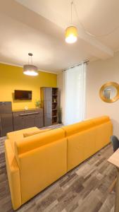 Un sofá naranja en una sala de estar con paredes amarillas en Spacious and bright house in the center - parking, en Verona
