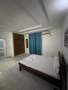 a bedroom with a bed and a blue curtain at Hôtel chez Marie Oyouma in Port-Gentil