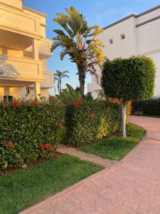 a walkway in front of a building with bushes and flowers at Ap13 marina golf course in Saïdia