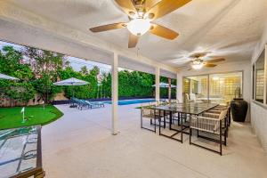 un soggiorno con ventilatore a soffitto, tavolo e sedie di The Palm Diamond a Luxury Poolside and Golf Oasis a Palm Springs