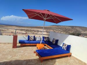 a patio with blue couches and a red umbrella at Sea Breeze 4 in Imsouane